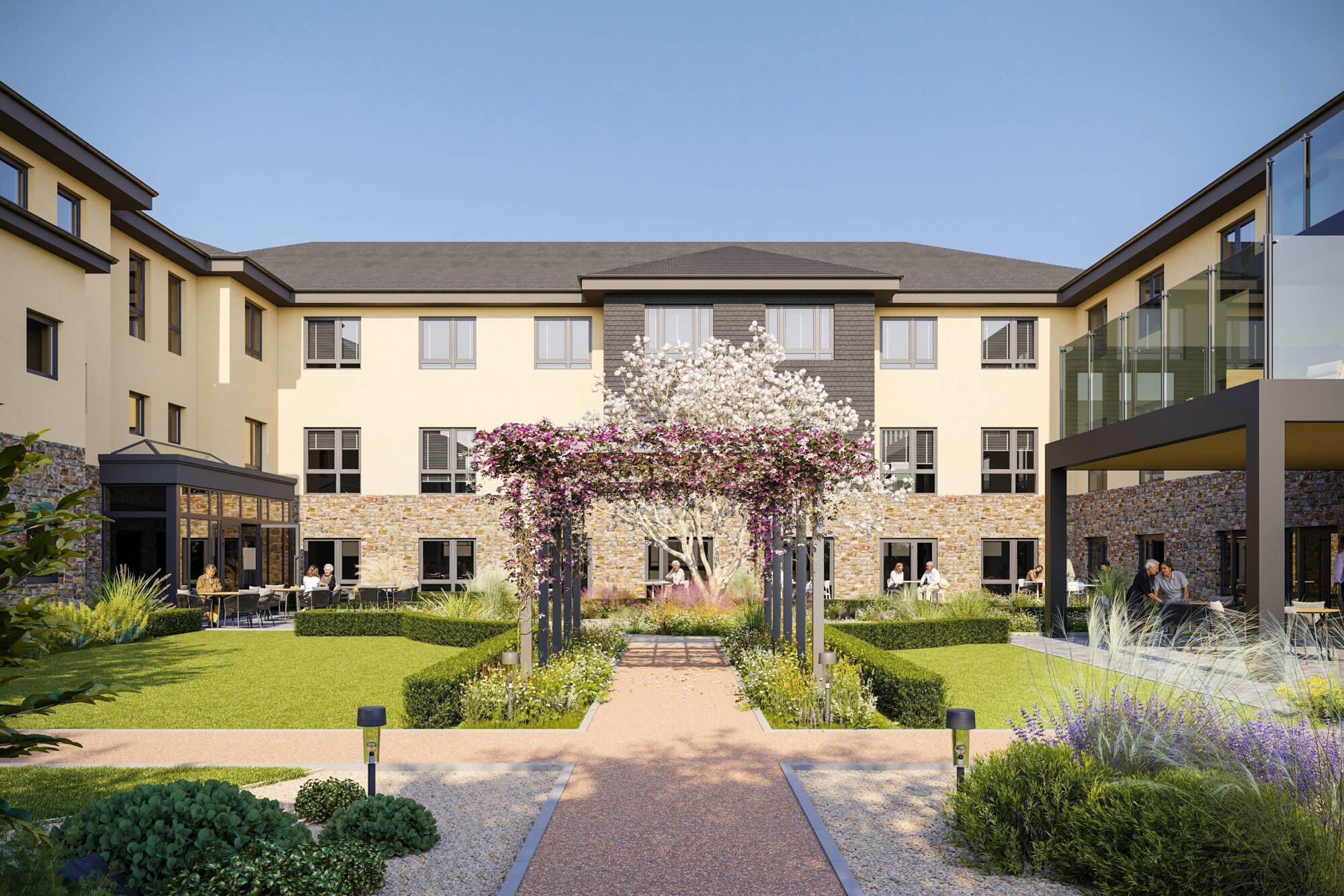 A modern three-story building with a landscaped courtyard featuring a pergola covered in flowering vines, manicured lawns, and various plants. People are seated at tables enjoying the outdoor space.